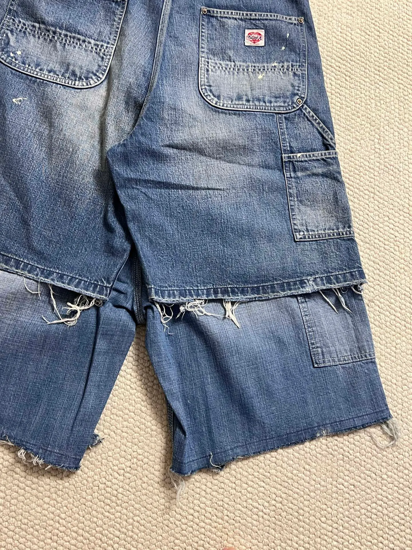 SAINT Mxxxxxx DOUBLE KNEE SHORTS/BLU Knee patches splashed with ink and water-splashed denim shorts. Denim blue S-XL. Custom-woven and dyed denim fabric with clear texture. Heavy-wash water-fading treatment to create local mottled fading/hole effects. Artificial distressing to simulate natural wearing marks. VINTAGE sense. Original consistent damage treatment. Hand-splashed ink and paint. Original consistent wash mark/pocket mark. Double knee patch. Rivet reinforcement. Improve functionality while enhancing design